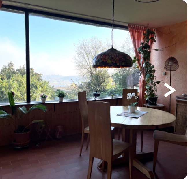 Wohnzimmer mit Panoramafenster, Esstisch und Blick ins Tal